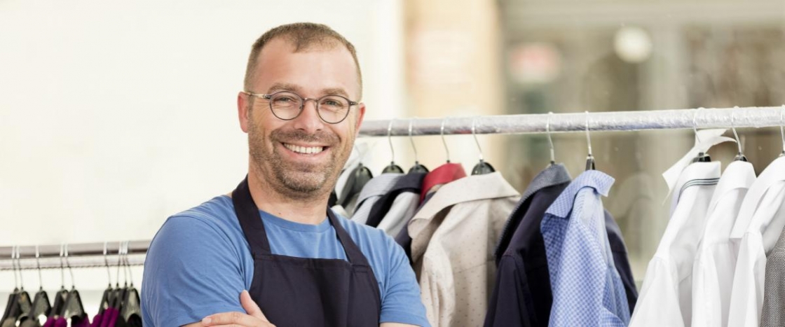 cleaner stands in front of dry cleaning rack